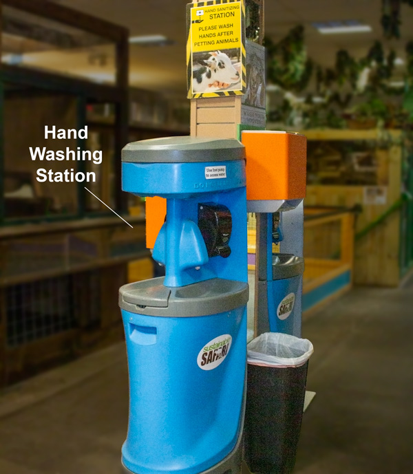 bright blue hand washing station with foot pump, soap, paper towel dispenser and trash bin.