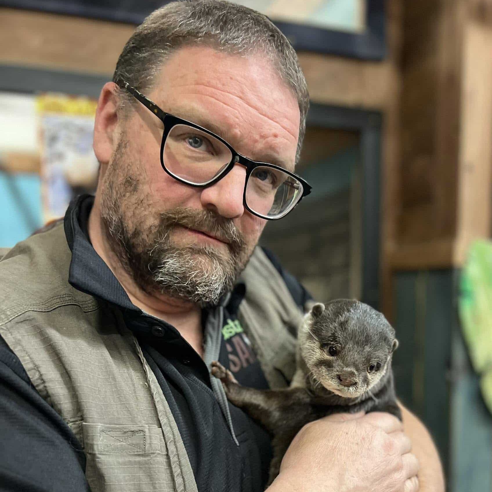 "Safari Bob" a man with glasses holding a river otter