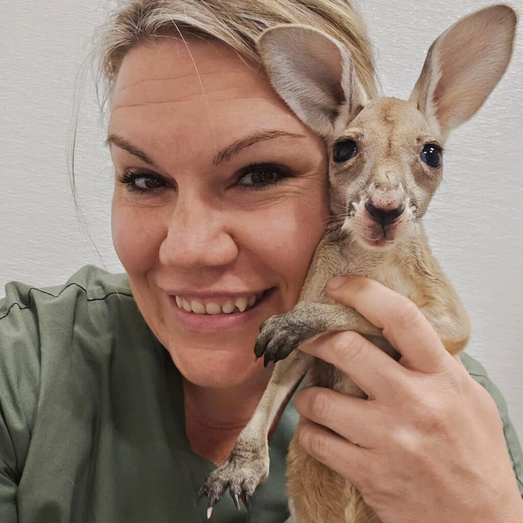 A woman holding a baby kangaroo